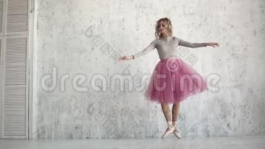 一位优雅的年轻芭蕾舞演员正在一个巨大的灯光窗口的背景下跳古典芭蕾。 一位芭蕾舞演员