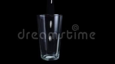 杯中的特写倒入白色酸奶。 框架。 在透明的大玻璃中倒入白色的浓稠液体，分离出黑色
