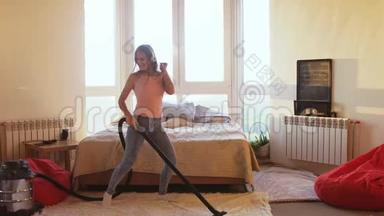 美丽的女人正在家里用现代吸尘器打<strong>扫地</strong>板，用耳机听音乐
