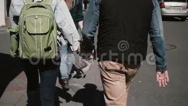在阳光明媚的日子里，年轻时尚的夫妇在街上散步。 男人和女人牵着手。
