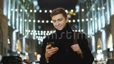 迷人的年轻人在夜城散步：看手机屏幕