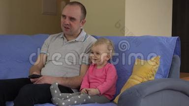 爸爸看电视，小可爱的女孩坐在沙发上。 4K