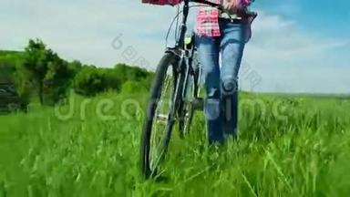 一个年轻的女人开着自行车穿过一片绿色的草地。 田园风光，美丽的春色
