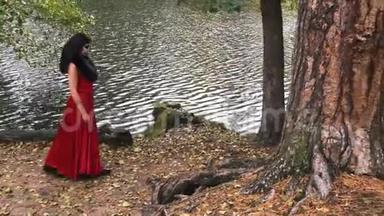一个穿着红色衣服的女人，穿着恐怖的万圣节服装在森林公园的树林间散步。