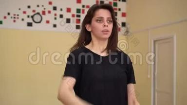 一位年轻漂亮的黑发女子在舞蹈室练习舞蹈