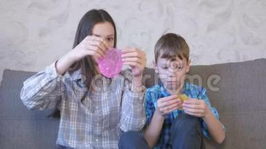 快乐的妈妈和儿子坐在沙发上玩黏液。 伸展的黏液透过黏液。