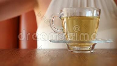 女孩把一块红糖放在一个透明的杯子里，上面有绿茶。 气泡上升。 4K，慢动作。