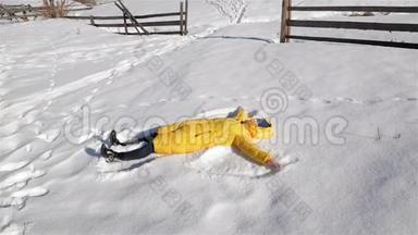 欢乐的女人正在玩冬季游戏。 黄夹克里的女孩躺在地上，让雪天使拥有