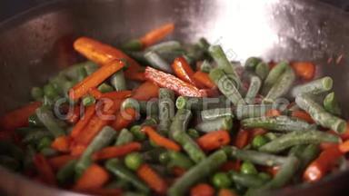 水流在装有蔬菜的热锅里. 橙色胡萝卜与冷冻豌豆和硅果酱<strong>亲密</strong>