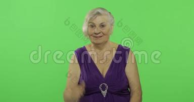 一位老妇人竖起大拇指，微笑着。 老奶奶。 铬键