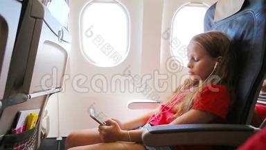 可爱的<strong>小女孩</strong>坐在靠窗的飞机上。 <strong>小</strong>孩在附近<strong>听音乐</strong>和发送信息
