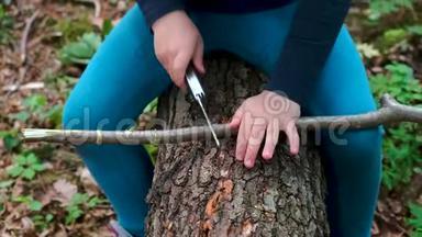 小女孩或男孩用瑞士刀在森林里锯一块木头，没有人