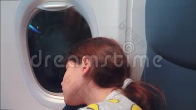 航空飞机概念。 坐在窗边的小女孩睡在飞机上。 夜间飞行的生活方式
