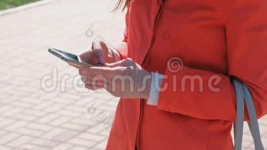 不可辨认的穿着红色外套的女人等着某人，检查她的手机，发短信。 <strong>特写双手</strong>。