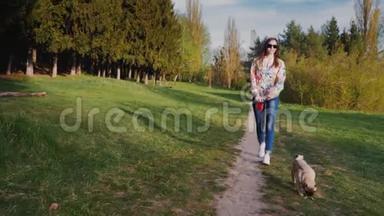 带着太阳镜和狗在公园<strong>散步</strong>的年轻女人。 沿着这条<strong>小路</strong>走在风景如画的大自然的背景下