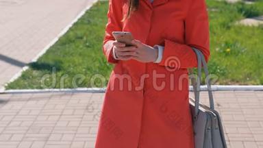 不可辨认的穿着红色外<strong>套</strong>的女人等着某人，检查她的手机，发短信。 特写<strong>双</strong>手。