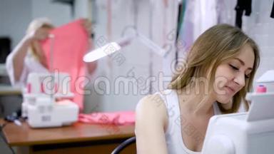快乐迷人的年轻女裁缝坐在缝纫机上缝制