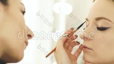 女人化妆师用化妆品刷化妆眼睛和眉毛作为美容模特。 快去化妆师那里