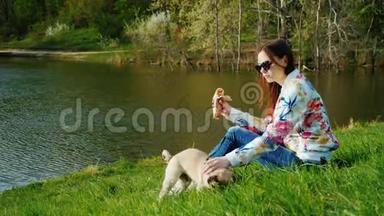轻松小<strong>吃</strong>在风景如画的公园与湖。 一个女人坐在草地上，一只<strong>热狗</strong>在<strong>吃</strong>，她旁边是一个