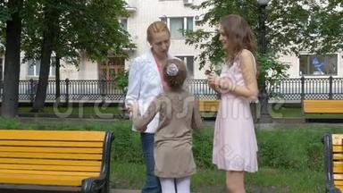 两个女朋友在公园里聊天。 小女孩跑到她妈妈身边拥抱她。