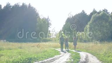 两个女孩和一个男人在夏天的时候，在日落的<strong>好天气</strong>里沿着乡间小路和森林散步