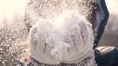 快乐的年轻女人在美丽的冬日玩得开心，享受新鲜的雪。 戴着温暖手套的女孩吹雪。 户外活动
