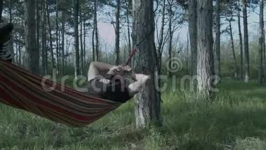一个年轻人在森林里的<strong>吊床</strong>上放松。 有胡子的帕森在<strong>吊床</strong>上摇摆。 一个熟睡的年轻人。