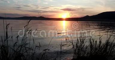 美丽的夏天日落在一个山湖上。 <strong>红日</strong>落山.. 波浪向岸上奔流