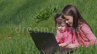 带着笔记本电脑在绿草上的小女孩。 阳光明媚的一天，公园里的姐妹们。 穿<strong>粉色</strong>衣服的小女孩带着笔记本电脑。 <strong>世界</strong>儿童