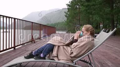 年轻女子在河边喝热<strong>咖啡</strong>或茶。 在山区度假胜地平静舒适的<strong>时光</strong>。