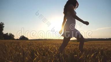 日落时，小女孩正沿着蓝天下的麦田奔跑。 女人正在草地上慢跑。 太阳照耀着
