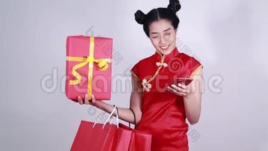 女士穿旗袍，带购物袋和礼物使用手机