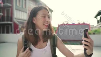 开朗美丽的年轻亚洲<strong>背包客</strong>博主女士在唐人街旅行时使用智能手机自拍。
