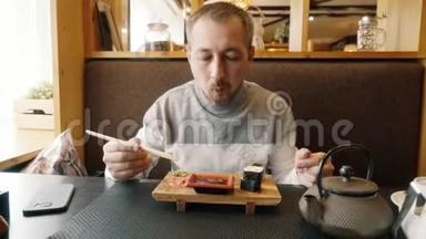 男人学会拿筷子做寿司。 咖啡馆里的一个男人正在吃面包卷。