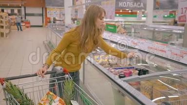 年轻女子在超市的冷藏区打开玻璃门，选择冰淇淋。