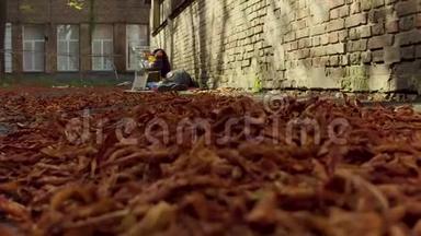 一片片落叶在地上，一个无家可归的人睡在地上。