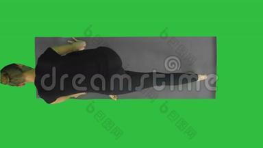 女人手里拿着一只面向下的狗，摆在绿色屏幕上的垫子上，Chroma键