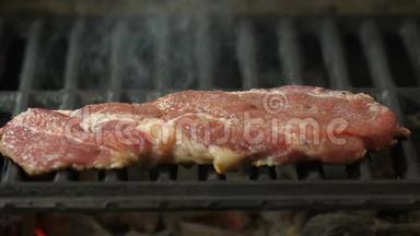 Semislotte牛排躺在烤架上，在烤架的背景烟雾中，观看侧面特写的视频