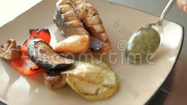 厨师在餐厅的盘子里加入了一片鲑鱼鱼、烤蔬菜和排骨的酱汁。 概念
