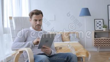 男人坐在<strong>休闲椅</strong>上浏览平板电脑上的互联网