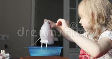 小女孩用搅拌器抽打奶油做蛋糕。