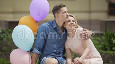 夏天，一对情侣在长凳上拥抱，一个人拿着气球，浪漫的约会