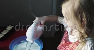 迷人的女孩用搅拌器抽打蛋糕奶油。