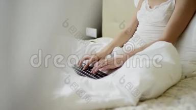 漂亮的女人在床上用手提电脑键盘打字