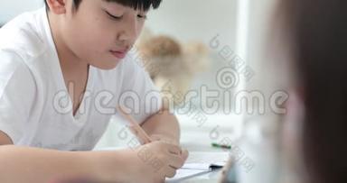 快乐的亚洲可爱男孩手拿铅笔，在家写作业。