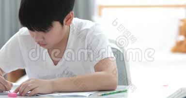 快乐<strong>的</strong>亚洲可爱男孩手拿铅笔，在家<strong>写作业</strong>。