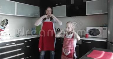 一位年轻的母亲和她的女儿在厨房里穿红色围裙。