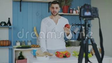英俊开朗的男人在家厨房的dslr摄像头上录制有关<strong>素</strong>食健康食品的<strong>视频</strong>博客