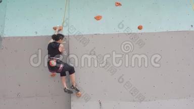 有<strong>登山</strong>设备的女<strong>登山</strong>运动员。 年轻的运动女孩爬上攀岩墙上的岩石。