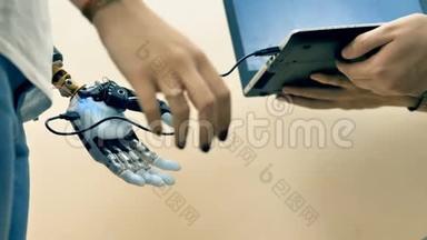 电子工程师使用笔记本电脑定制人手上的机器人手臂。
